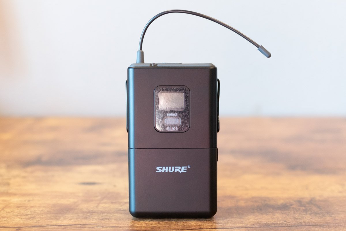 Shure wireless microphone transmitter on a wooden surface with a blurred background