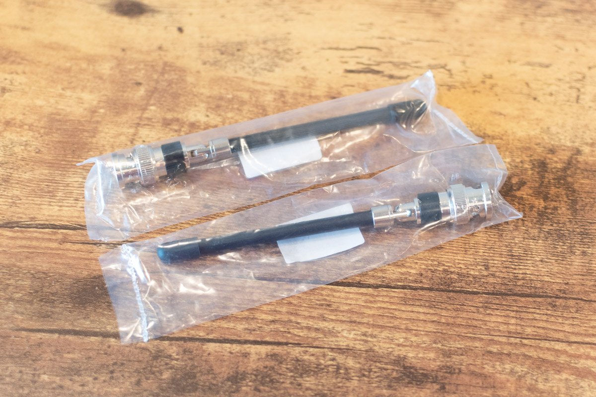 Two pens in clear plastic packaging on a wooden surface